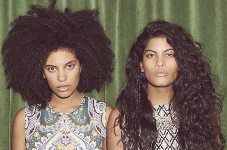 Two sisters pose by the curtain.